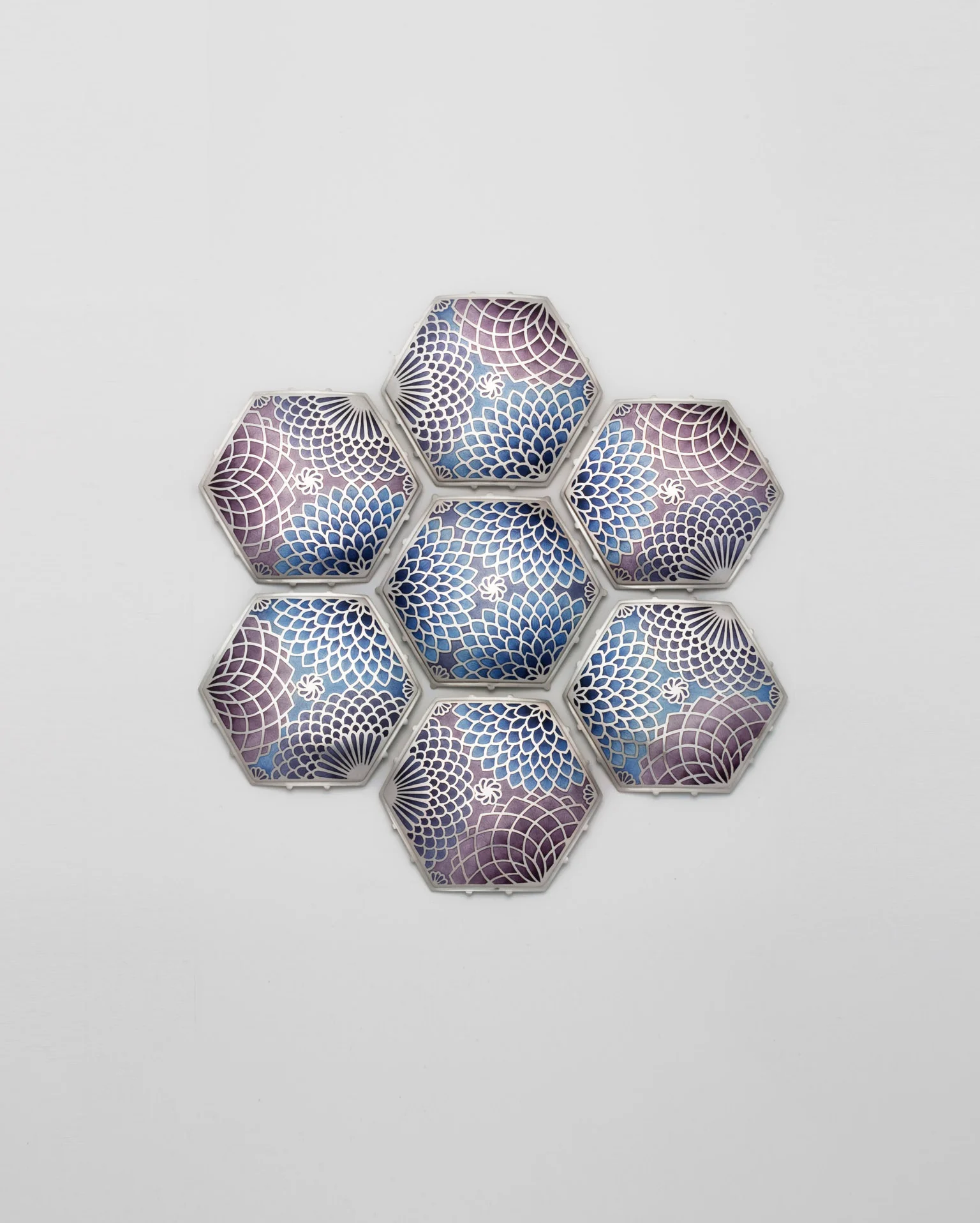 Seven hexagonal pieces with intricate floral patterns in blue, violet and silver.