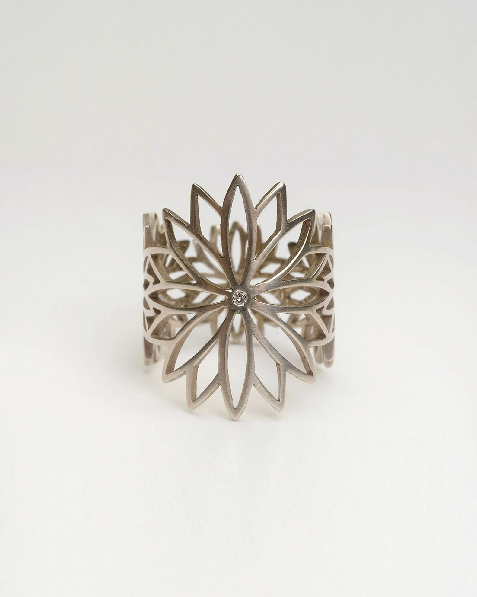 A silver-coloured cuff formed from an openwork flower with a small central stone.