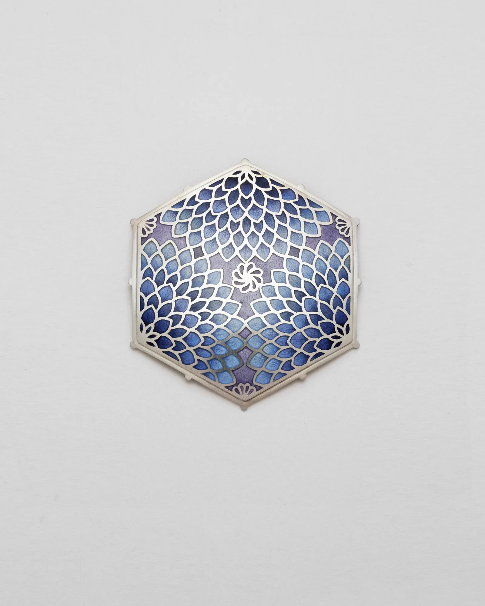 A hexagonal blue piece with an intricate silver-coloured floral pattern.