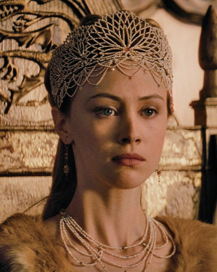 A film character wearing a latticework crown, drop earrings and layered pearl necklaces.